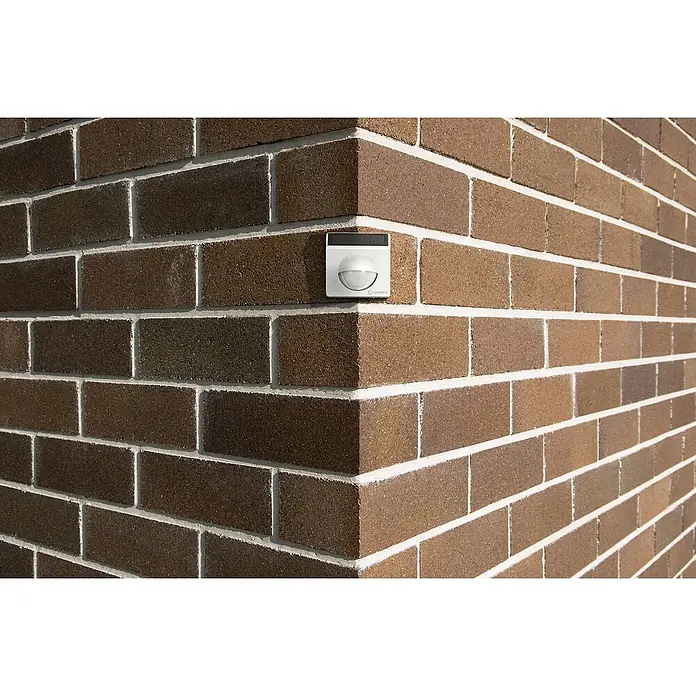 Ledvance Smart+ WiFi Bewegungsmelder - Weiß, Reichweite ca.: 9 m - Außenaufnahme einer LEDVANCE Außenleuchte mit Bewegungsmelder an einer braunen Backsteinmauer, die eine effektive Beleuchtungslösung bietet.