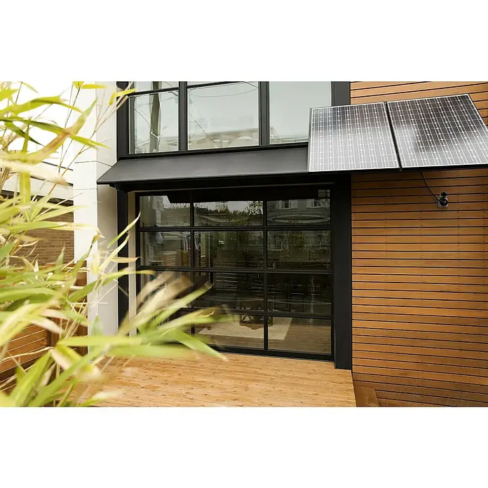 Osram Smart-Steckdose mit Deckel matter - Außen, IP44, Schwarz, 16 A, 1 Stk. - Nahaufnahme eines Hauses mit Glasfenstern und Sonnenkollektoren, die eine moderne und nachhaltige Architektur betonen.