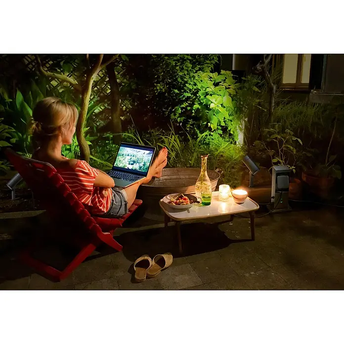 Ledvance Smart+ WiFi Energiesäule mit integriertem WLAN-Repeater und zwei smarten Steckdosen - Anthrazit - Entspanntes Abendessen im Freien mit einem Laptop, einer Flasche Wein und Kerzen auf einem kleinen Tisch.