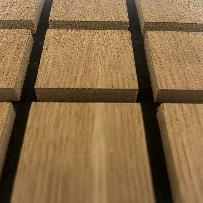 acous Akustikpaneelmuster Blockbuster - 150 x 150 x 10,3 mm, Eiche Rustikal - Nahaufnahme von Akustikpaneelen aus Holz, die auf einer dunklen Oberfläche angeordnet sind, ideal zur Schallabsorption und Verbesserung der Raumakustik.