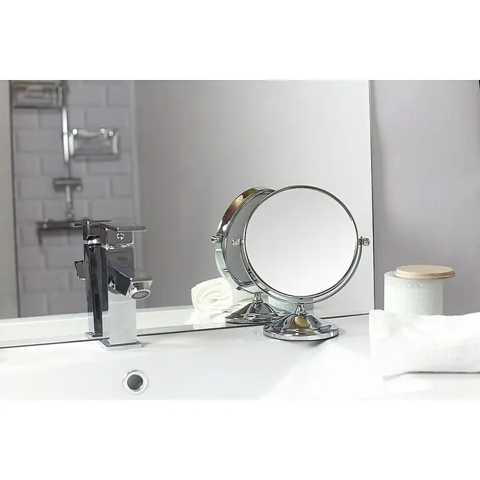 Deblanch Espejo cosmético - 15 x 15 cm, Redonda, Cromo, Aumento 1: 300 %, Aumento 2: 700 % - Primer plano de un espejo de aumento de doble cara cromado y redondo sobre un tocador de baño blanco.
