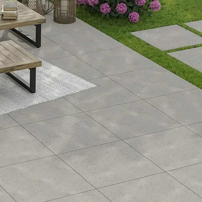 Terrassenfliese Garden Family Lightgrey - 60 x 60 x 2 cm, Hellgrau, Matt - Großformatige, graue Terrassenplatten verlegt auf einer Terrasse mit einem Outdoor-Tisch und Stühlen.
