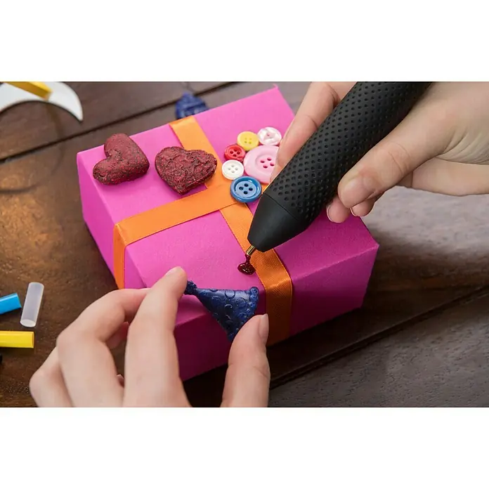 Bosch Akku-Heißklebestift GlueyFarbe: Evergreen - Nahaufnahme eines Bastelprojekts mit einem Heißklebestift, der zum Dekorieren eines rosa Geschenks verwendet wird.