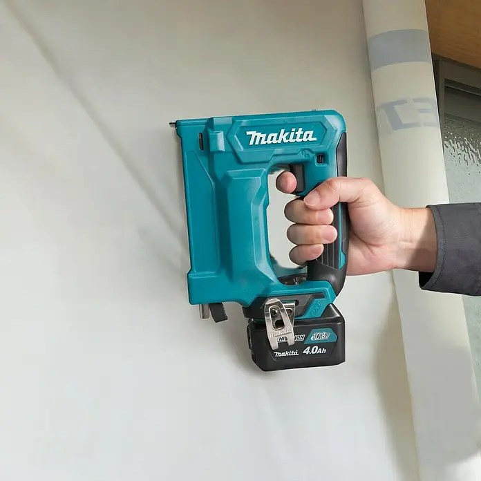 Makita CXT 12V max. Akku-Tacker ST113DSMJ - 12 V, 2 Akkus, 4 Ah - Nahaufnahme eines Makita Akku-Tackers. Das Werkzeug ist blaugrün und schwarz und wird von einer Hand gehalten.