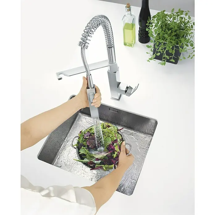 Grohe Eurocube Spültischarmatur - Edelstahl, Matt, Anzahl Strahlarten: 2 Stk. - Eine Person wäscht Salat in einem Spülbecken mit einer modernen Edelstahlarmatur. Die Armatur ist ein Blickfang in der modernen Küche.