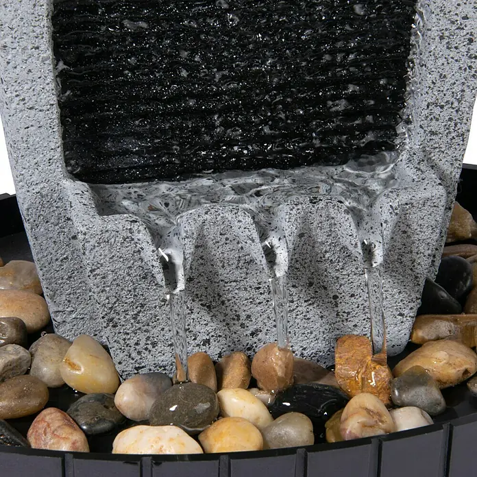 Dobar Gartenbrunnen - 20,5 x 16,5 x 28 cm, Kunststoff, Grau/Schwarz - Nahaufnahme eines Zimmerbrunnens mit Wasser, das über Steine in ein Becken fließt. Die beruhigende Atmosphäre wird durch das sanfte Plätschern verstärkt.