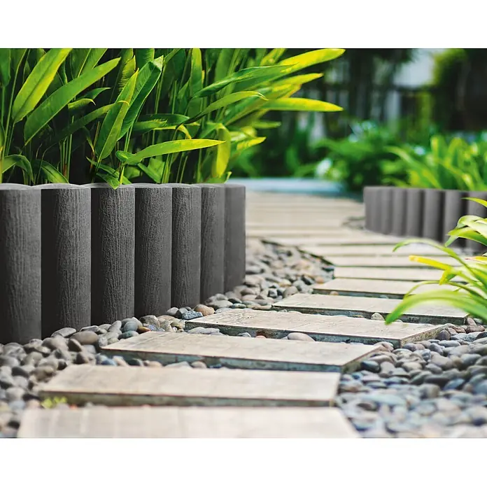 Rundpalisade - Anthrazit, Kunststoff - Eingefasster Gartenweg mit Steinen und Betonplatten. Die dunklen Beetumrandungen heben die Pflanzen und den Weg hervor.
