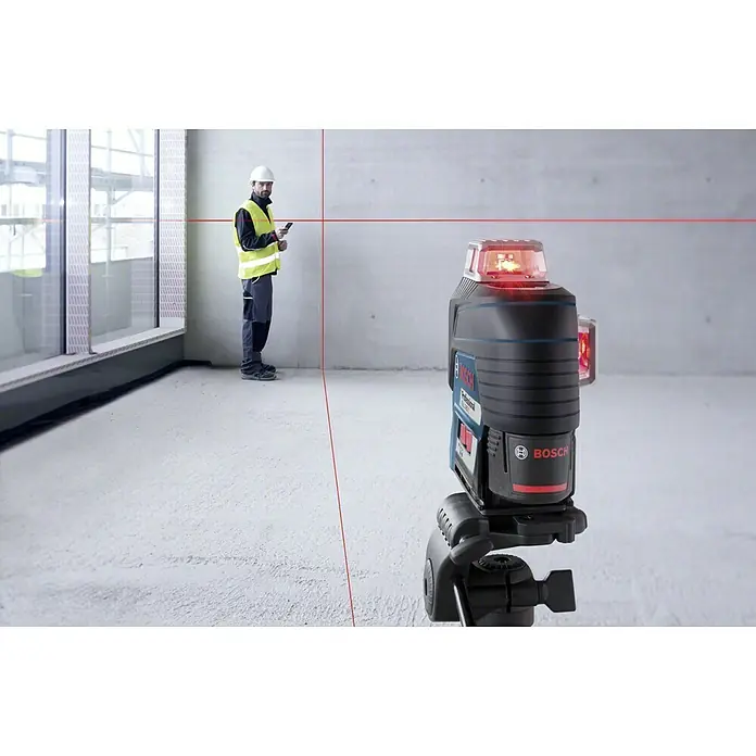 Bosch Professional Linienlaser GLL 3-80C - Max. Arbeitsbereich: 30 m, 5 -tlg. - Das Bild zeigt einen Bosch Professional GCL 2-50 G Linienlaser, der rote Laserlinien an Wände projiziert, während ein Arbeiter im Hintergrund steht.