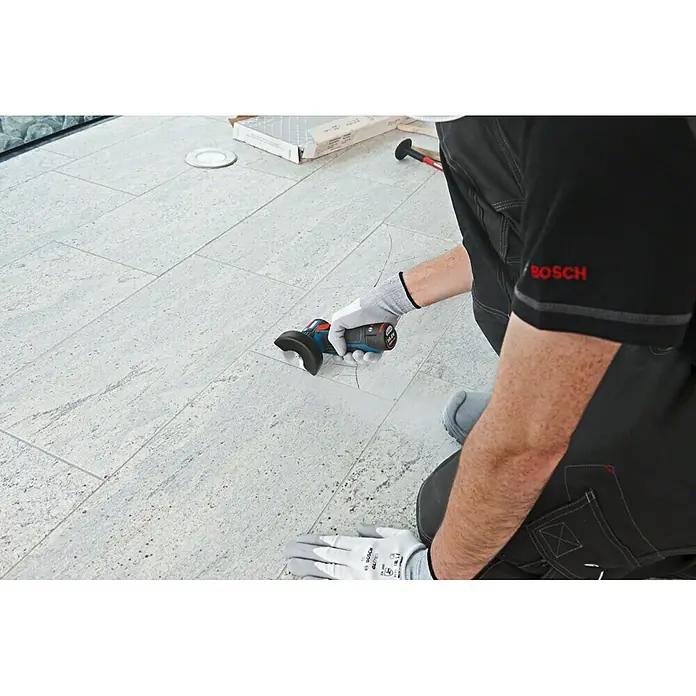 Bosch Professional Akku-Winkelschleifer GWS 12V-76 L-Boxx - Ohne Akku, Durchmesser Scheibe: 76 mm, 19.500 U/min - Nahaufnahme eines Akku-Winkelschleifers von Bosch in Benutzung, ideal zum Schneiden von Fliesen mit Präzision und einfacher Handhabung.