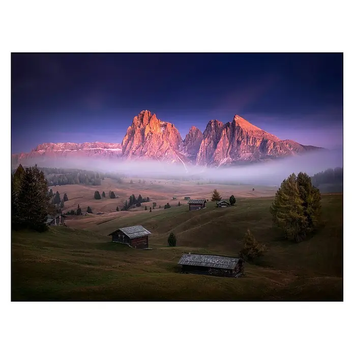ProArt Leinwandbild - Mist & Mountain, B x H: 120 x 90 cm - Malerische Landschaft mit Almhütten, sanften Hügeln und den markanten Dolomiten im Hintergrund, gehüllt in sanften Nebel.