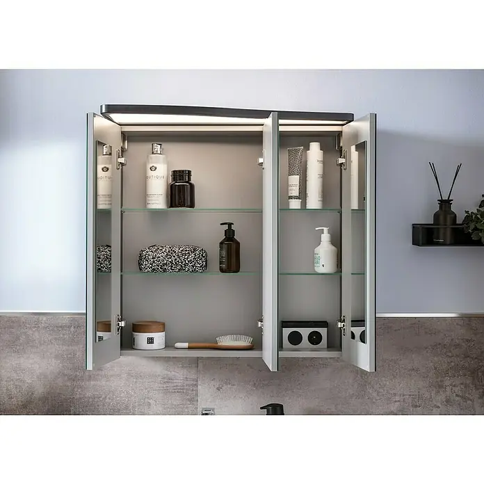 Camargue Lineo LED-SpiegelschrankB x H: 70,4 x 70,2 cm, Berg Eiche, DIN Anschlag: Links - Offener Badezimmerschrank mit diversen Kosmetikartikeln, darunter Flaschen, Tiegel und Behälter auf Glasböden, beleuchtet mit integrierten Lichtern.