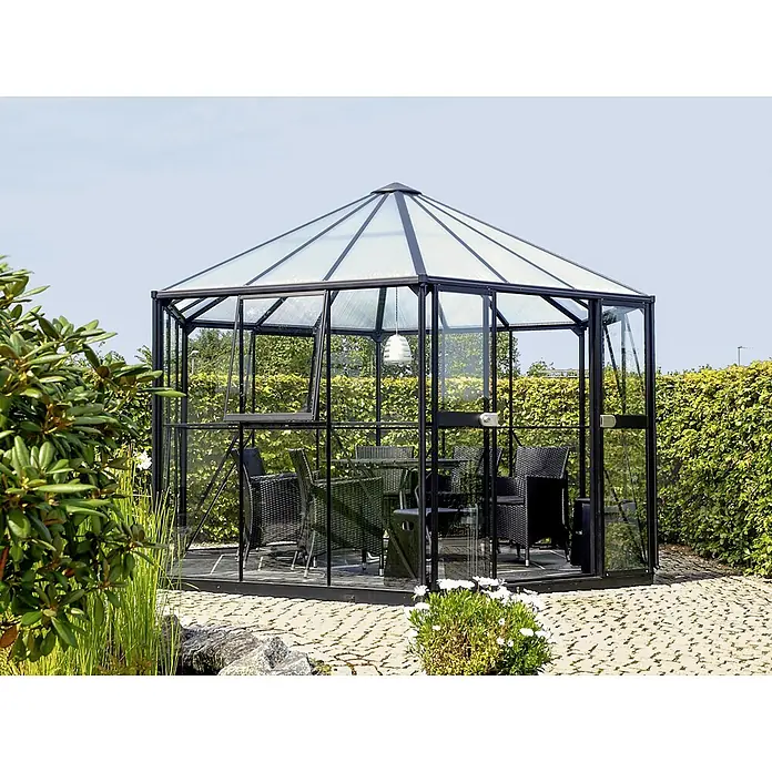 Vitavia Gewächshaus Juno 9000 - Außenmaß inkl. Dachüberstand (B x T): 336 x 383 cm, 3 mm, Anthrazit/Schwarz - Ein Pavillon-Gewächshaus mit einem Tisch und Stühlen im Inneren, umgeben von grüner Natur, bietet einen friedlichen Rückzugsort.