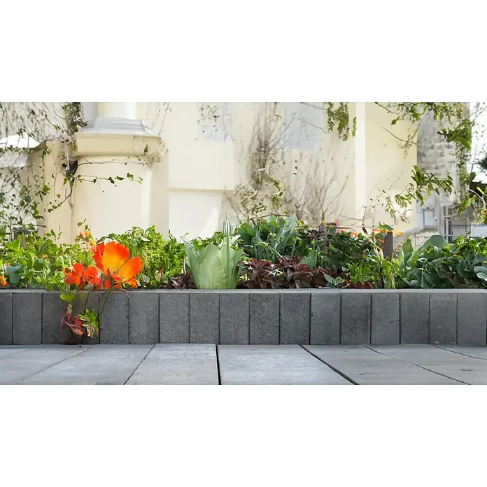 EHL Palisade Bord Lima - 6 x 50 x 25 cm, Grau, Beton - Ein Blumenbeet mit orangefarbenen Blüten vor einem Gebäude, das eine friedliche und natürliche Atmosphäre schafft.