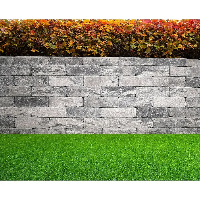 EHL Mauerstein Anzio Light - 25 x 18 x 15 cm, Grau/Anthrazit, Beton - Eine graue Steinmauer mit bunten Pflanzen oben und grüner Rasenfläche unten, die die Mauer umgibt. Ideal für Garten- oder Landschaftsbauprojekte.