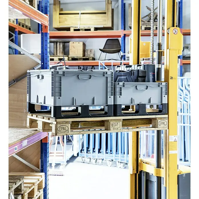 Surplus Systems Deckel - Passend für: Surplus Systems Euronormbox 80 x 60 cm, L x B: 80 x 60 cm - Graue Kunststoffbehälter auf einer Palette, die von einem gelben Gabelstapler in einem Lagerhaus angehoben wird.