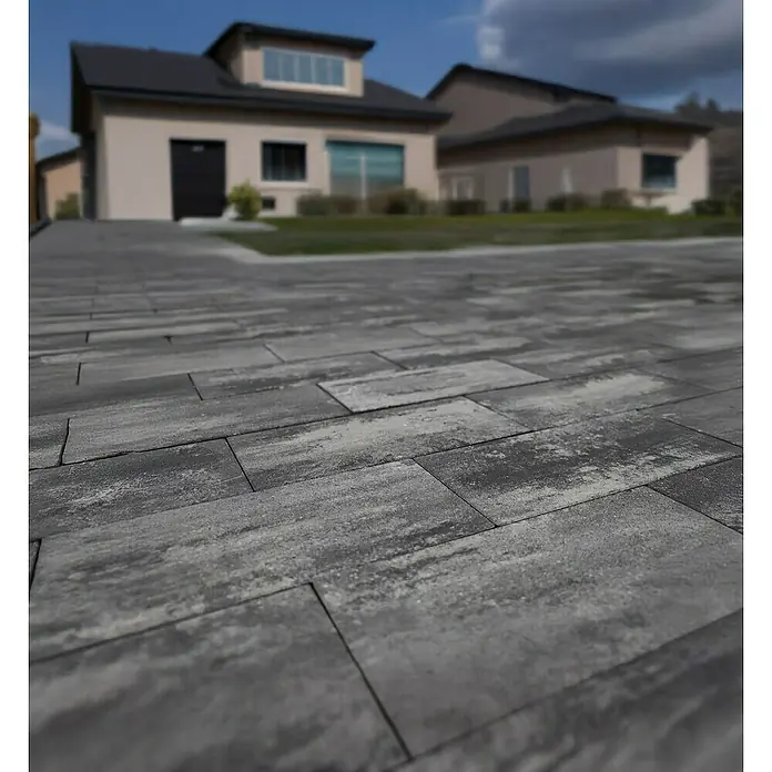 EHL Terrassenplatte Olinda - 40 x 20 x 4 cm, Grau/Anthrazit, Beton - Das Bild zeigt eine graue Pflasterstein-Einfahrt vor einem Wohnhaus an einem sonnigen Tag. Die Pflastersteine sind das Hauptmerkmal des Bildes.