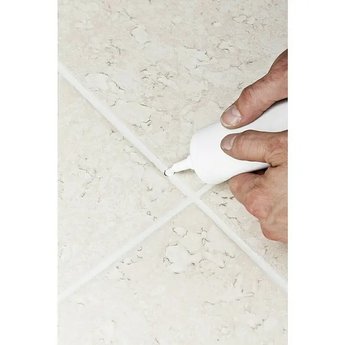 Knauf Fugenreparatur - Silbergrau, 250 g - Ein Handwerker, der mit einer weißen Kartusche die Fugen zwischen hellen Fliesen ausbessert, um das Erscheinungsbild zu verbessern.