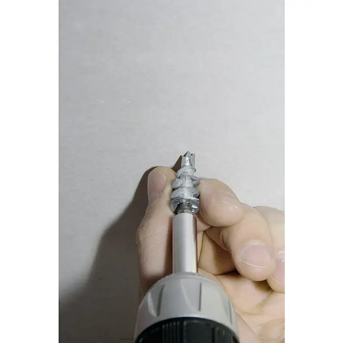 Knauf Gipsplatten Metalldübel - Länge Dübel: 37 mm, Länge Schraube: 35 mm - Nahaufnahme einer Hand, die mit einem Schraubenzieher einen selbstschneidenden Dübel in eine Wand schraubt.