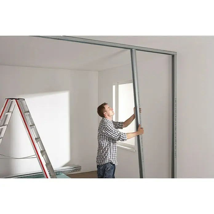 Knauf CW-Standprofil - 3.500 x 100 x 50 mm, Stahl - Mann montiert Trockenbauwand mit Metallprofilen. Konstruktion mit Leiter und Material für den Innenausbau.