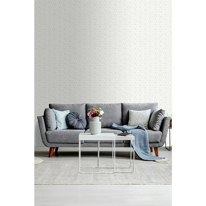 A.S. Création Metropolitan Stories Vliestapete Lizzy - Weiß/Grau, 3D-Optik, 10,05 x 0,53 m - Wohnzimmer mit grauem Sofa, weißem Tisch und geometrischer Tapete. Das elegante Design verleiht dem Raum eine moderne Note.