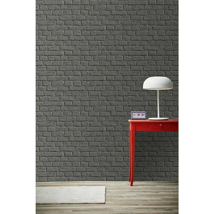 A.S. Création Metropolitan Stories Vliestapete Steine - Dunkelgrau, Steinoptik, 10,05 x 0,53 m - Graue Ziegelwand mit rotem Tisch, weißer Lampe und Teppich für ein elegantes, modernes Raumambiente. Stilvolle Dekoration mit Charme.