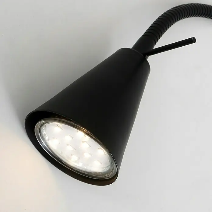Briloner Foco de pared LED Comfort Light - Negro, 4 W - Primer plano de una moderna lámpara de lectura LED negra con brazo flexible, montada sobre un fondo blanco.