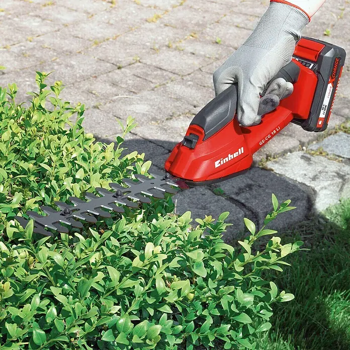 Einhell Power X-Change 18V Akku-Gras- & Strauchschere GC-CG 18 Li-Solo - 18 V, Li-Ionen, Ohne Akku, 100 mm - Akku-Grasschere GE-CG 18 Li mit Handschuh beim Heckenschneiden im Garten.