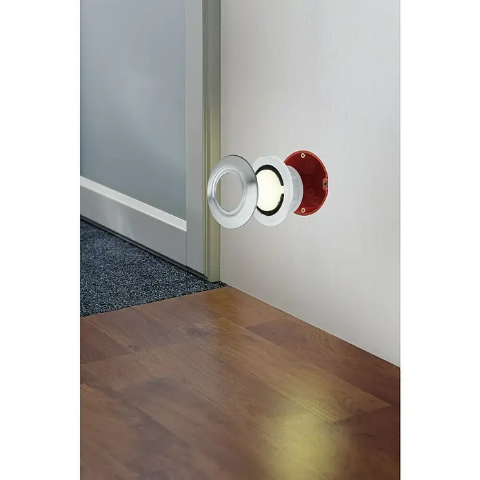 Paulmann Special Line LED-Einbauleuchten-Abdeckung - Edelstahl, Durchmesser: 86 mm, IP65 - Nahaufnahme einer runden, eingelassenen Wandleuchte mit silberner Blende und roter Fassung in einem Raum mit Holzboden.