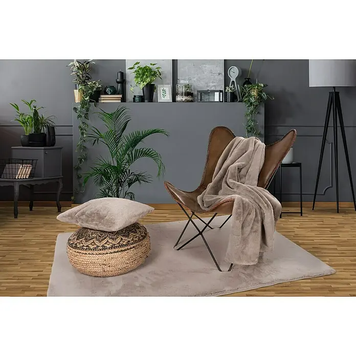 Decke Happy - Taupe, 200 x 150 cm, 100 % Polyester - Nahaufnahme eines braunen Schmetterlingsstuhls mit einer Decke auf einem grauen Teppich, der ein gemütliches und stilvolles Interieur zeigt.