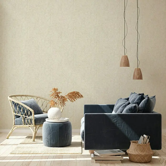 A.S. Création New Walls Vliestapete I - Beige, Uni, 10,05 x 0,53 m - Elegantes Wohnzimmer mit einem blauen Samtsofa, einem Rattansessel und stilvollen Pendelleuchten, die eine gemütliche Atmosphäre schaffen.
