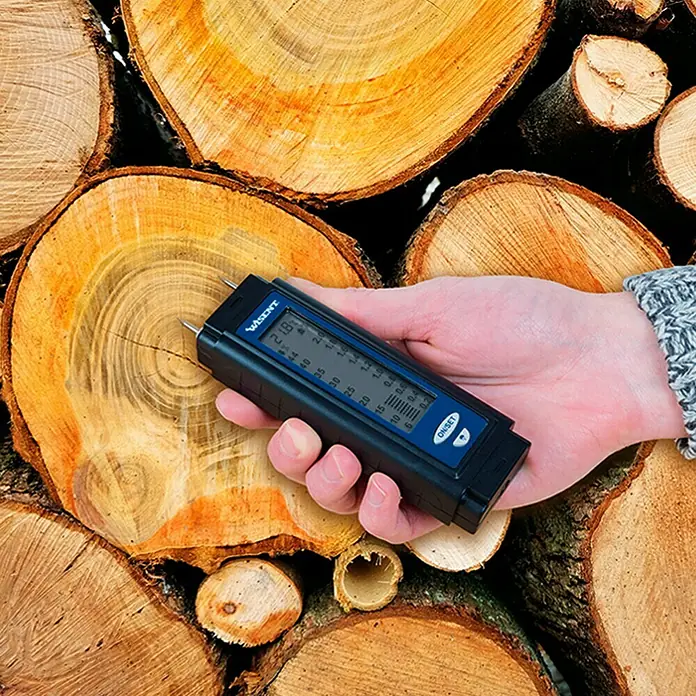 Wisent Feuchtigkeitsmessgerät - Messbereich: 0,2 - 2 % (Baufeuchte) - Nahaufnahme eines Holzfeuchtemessgeräts, das in ein Holzscheit gesteckt wird, um den Feuchtigkeitsgehalt zu prüfen.