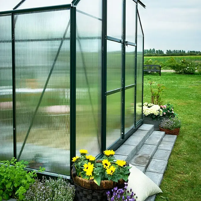 Halls Gewächshaus Magnum 128 - Außenmaß inkl. Dachüberstand (B x T): 257 x 384 cm, Material Seitenwand: Kunststoff, 6 mm, Grün - Detailaufnahme eines Gewächshauses mit Blumenkästen und Bepflanzung im Vordergrund. Schönes Gartendesign mit Pflanzen.