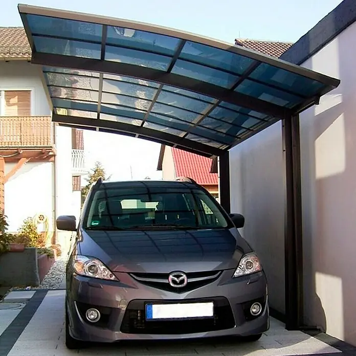 Ximax Carport Portoforte 60 - Außenmaß inkl. Dachüberstand (B x T): 2,7 x 4,95 m, Einzelcarport, Mattbraun, Schneelast: 75 kg/m² - Ein grauer Mazda 5 steht unter einem modernen Carport mit Stahlrahmen und durchsichtigem Dach, der Schutz vor Witterungseinflüssen bietet.
