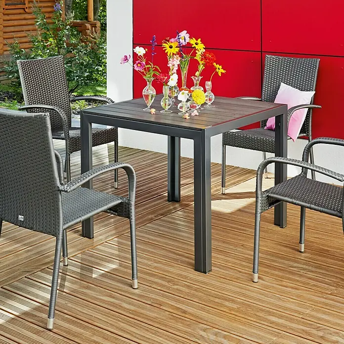 Sunfun Neila Sillón de jardín Neila - An x Pr x Al: 56 x 63 x 94 cm, Poliratán, Apilable, Gris plata - Juego de jardín con mesa gris y cuatro sillas de mimbre en una terraza de madera, decorado con flores de colores en pequeños jarrones.
