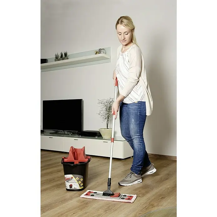 Sprintus Bodenwisch-Set Click N Press + Staubmop - 12 l, 5 -tlg., Materialzusammensetzung Bezug: 80 % Mikrofaser, 20 % weiche Abrasivborsten - Frau wischt Holzboden mit dem Quick'n'Press Wischmop-Set, das einen Eimer mit Auswringer enthält, für eine effiziente Reinigung.