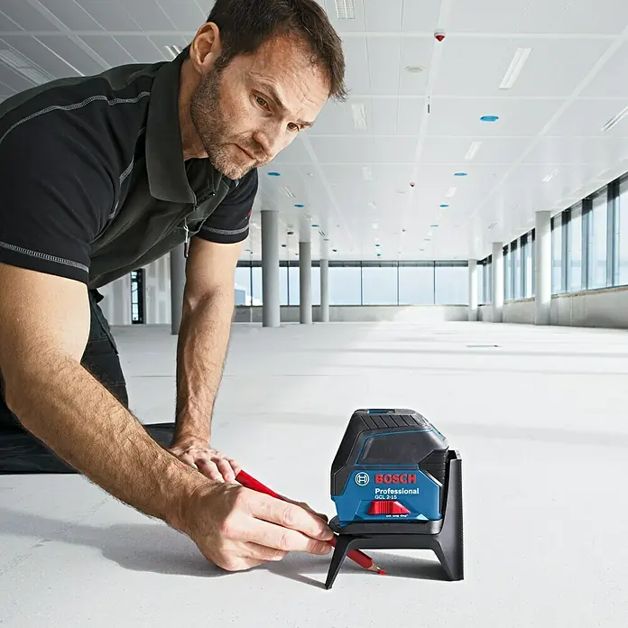 Bosch Professional Kombilaser GCL 2-15 - Arbeitsbereich: Ca. 15 m, 5 -tlg. - Ein Mann benutzt einen Bosch Professional GCL 2-15 Kreuzlinienlaser auf einem hellen Boden.