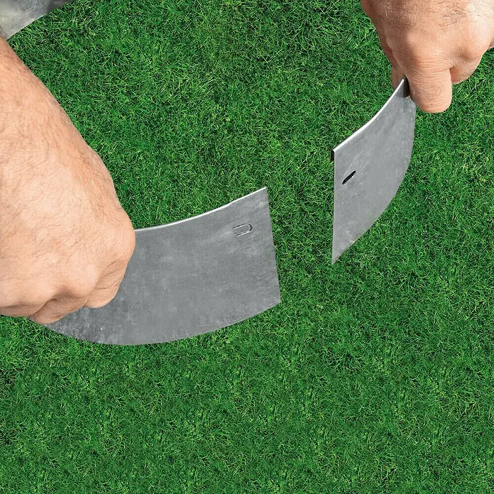 Bellissa Rasenkante Kreis - 40 x 13 cm, Stahl, Verzinkt - Zwei gebogene Metallstücke werden über einem grünen Rasen von Händen gehalten, vermutlich Teile einer Rasenkante.