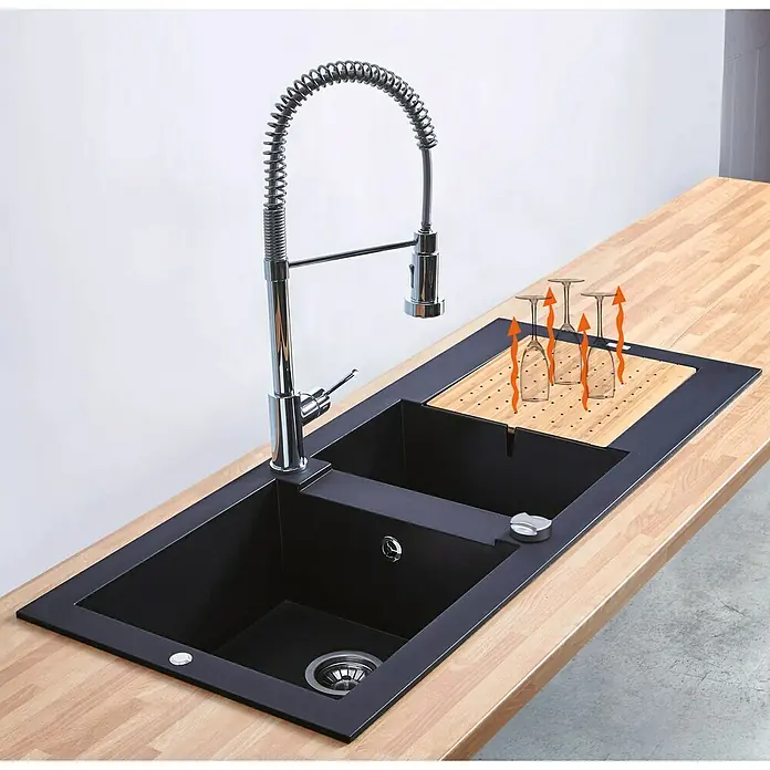 Carea Einbauspüle Eole - 118 x 50 cm, Betongrau - Ansicht einer schwarzen Küchenspüle mit Abtropfgestell und einem modernen, spiralförmigen Wasserhahn auf einer hellen Holzarbeitsplatte.