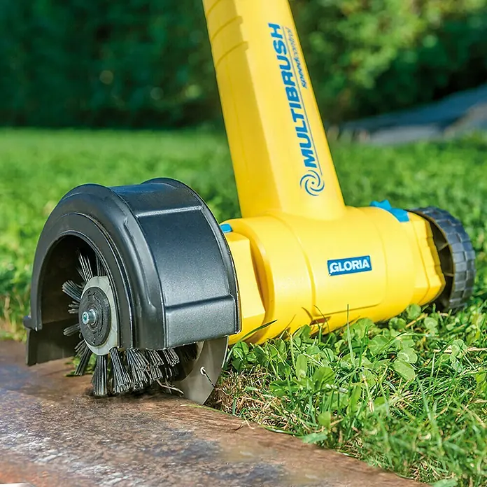 Gloria Rasenkantenschneider Cut & Brush - Passend für: Gloria Bodenreinigungsbürsten MultiBrush speedcontrol/li-on - Die Gloria MultiBrush Kehrmaschine im Einsatz gegen Unkraut und Moos auf einer Steinfläche im Garten.