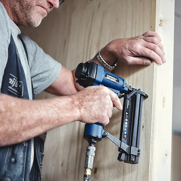 Rapid Nagel Typ 8 - Länge: 50 mm, 5.000 Stk., Verzinkt - Ein Handwerker benutzt einen Rapid Druckluftnagler an einem Holzrahmen, um präzise Nägel zu setzen.