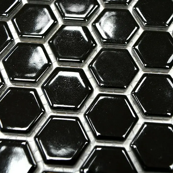Mosaikfliese Hexagon Uni HX 060 - 26 x 30 cm, Schwarz, Glänzend - Nahaufnahme von glänzenden, schwarzen Sechseckfliesen, die auf einem weißen Netz angeordnet sind und ein modernes Design schaffen.