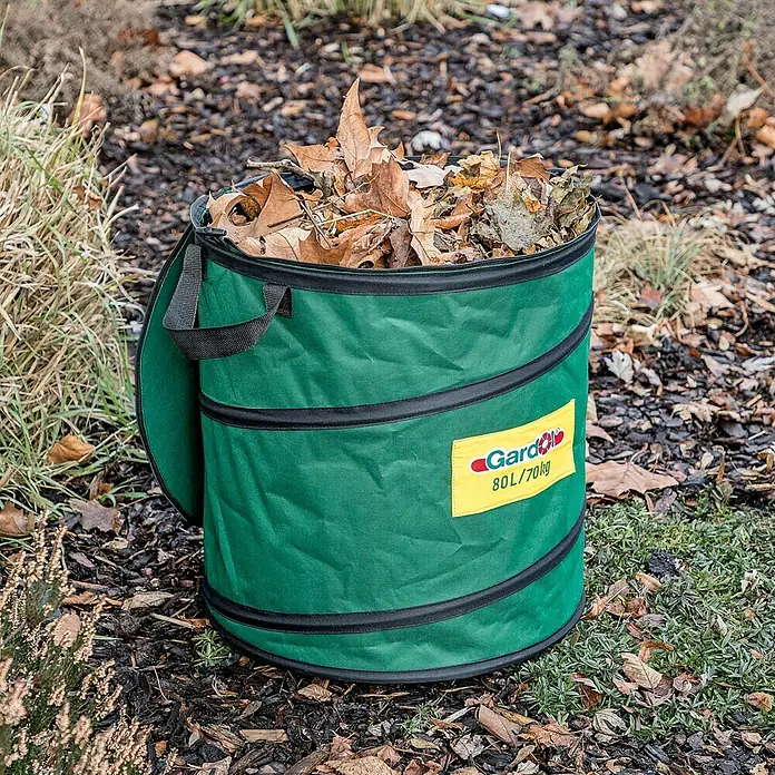 Gardol Premium Saco para desechos de jardín Pop-Up - 80 l, Ø x Al: 46 x 48 cm - Una bolsa de jardín verde de Gardol llena de hojas de otoño está en un césped en el jardín.