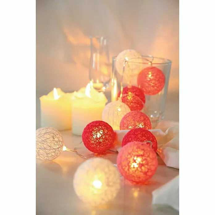 Globo Guirnalda luminosa LED Venuto - Para interior, Longitud del cable: 1,35 m, Multicolor - Primer plano de bolas de luces rojas y blancas con velas y vasos, creando un ambiente cálido y acogedor.