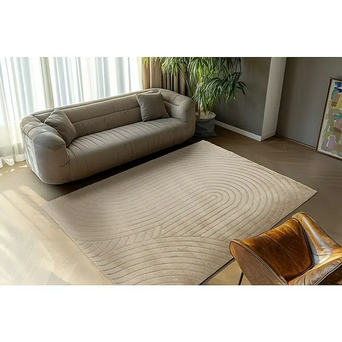 Fellteppich Zen - Beige, 150 x 80 cm, 100 % Polyester - Ein beiger Teppich mit einem modernen, geschwungenen Design liegt in einem stilvollen Wohnzimmer unter einem Sofa.