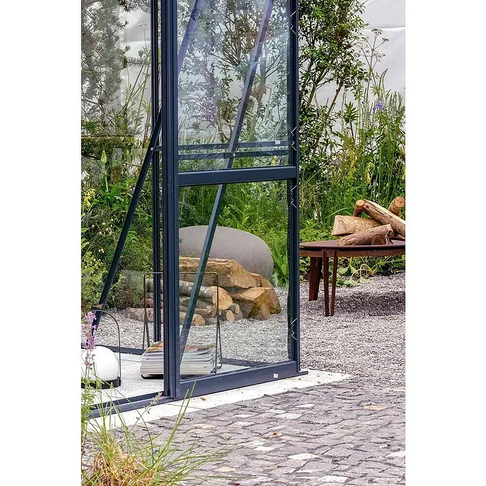 Halls Gewächshaus Magnum 108 - Außenmaß inkl. Dachüberstand (B x T): 257 x 322 cm, Material Seitenwand: Kunststoff, 6 mm, Grün - Nahaufnahme eines modernen Gewächshauses mit dunklem Rahmen, das sich nahtlos in eine üppige Gartenlandschaft einfügt.