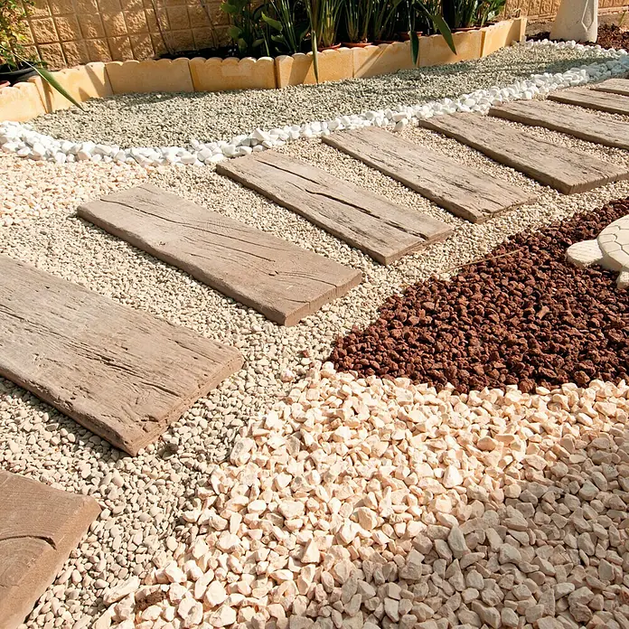 Traviesa de madera - 90 x 25 x 5 cm, Hormigón - Esta foto muestra un camino de jardín decorativo con piedras de madera, rodeado de varios cantos rodados ornamentales de colores y plantas.