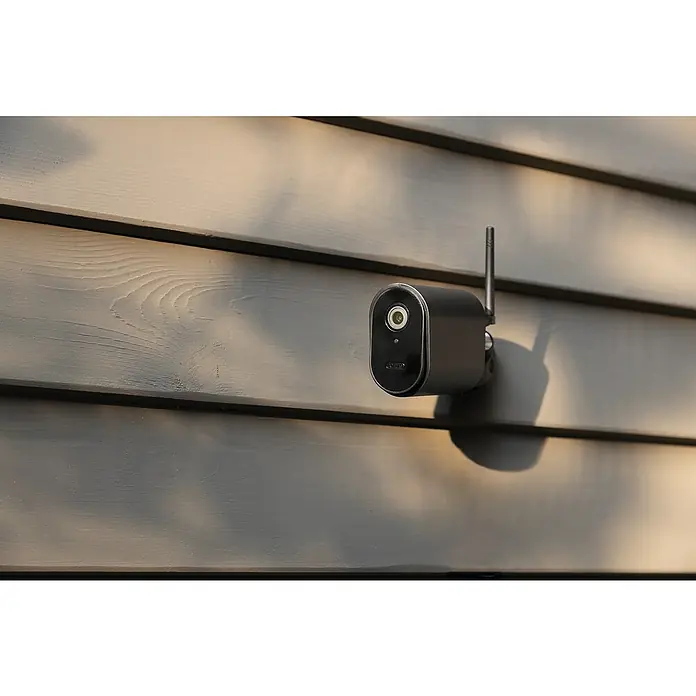 Abus Überwachungskamera Smartlook WLAN PPIC54520 BK - Auflösung: 4K Ultra HD/HDR, Schwarz - Diese Nahaufnahme zeigt eine kabellose Arlo Überwachungskamera an einer Hauswand, die Sicherheit und Komfort bietet.