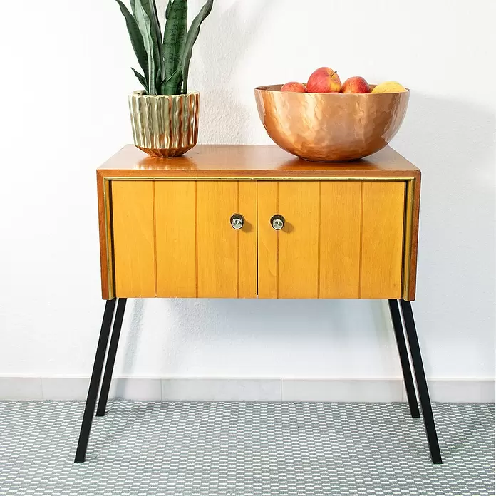 Wagner System Möbelfuß - L x B x H: 20 x 20 x 710 mm, Stahl - Mid-Century-Beistelltisch aus Holz mit schwarzen Haarnadelbeinen, Messingakzenten, einer Pflanze und einer Kupferschale.
