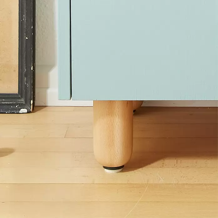 Wagner System Möbelfuß - Ø x H: 60 x 100 mm, Holz - Hellblaues Möbelstück mit rundem Naturholzbein und Filzgleiter auf hellem Holzboden.