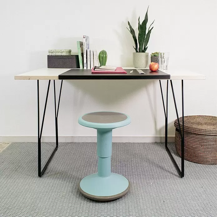 Wagner System Möbelfuß - L x B x H: 600 x 90 x 710 mm, Stahl - Türkiser ergonomischer Hocker mit grauem Sitz und Bodenring, unter einem Schreibtisch platziert.